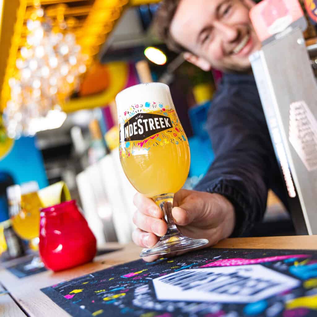 VandeStreek special sustainable beer filled glass held by a smiling man