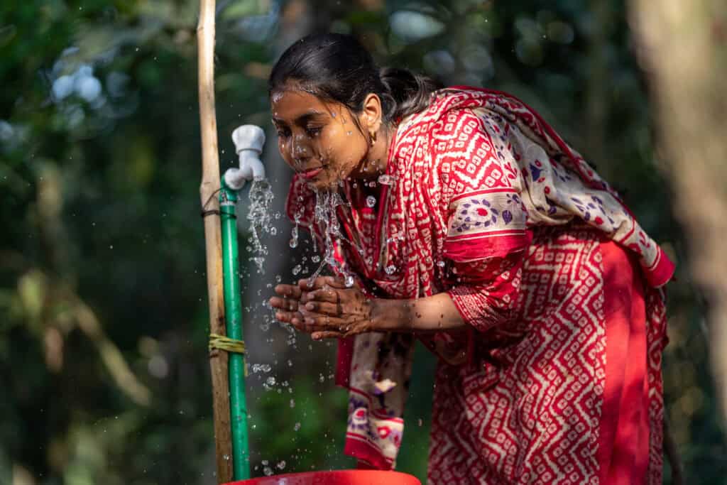 Women washing het face with clean water from watergrids installed by Max Tapwater in Bangladesh
