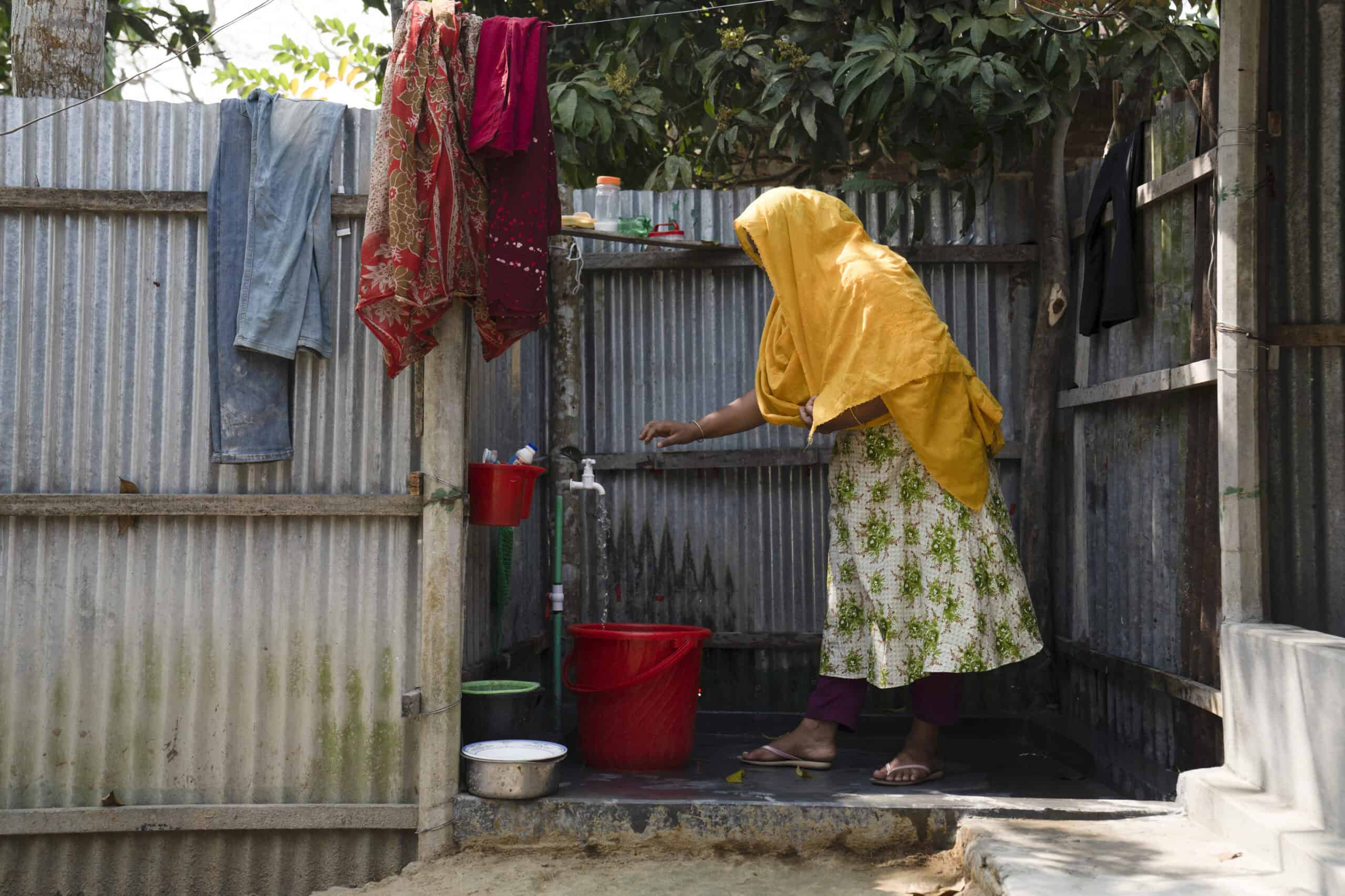 Woman washes clothes with clean water provided by Max Tapwater in Bangladesh